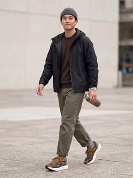 Olive green cargo pants paired with a black technical windbreaker and a neutral-toned beanie for a functional outdoor aesthetic.