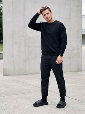 Lightblaze Slides – A monochromatic outfit featuring black nylon track pants and a matching black tech-fleece sweatshirt for a sleek, urban vibe.