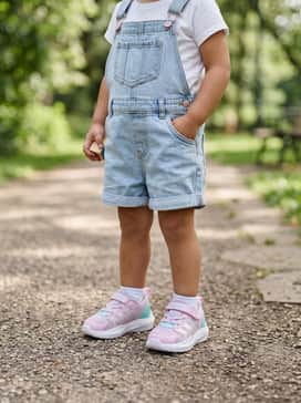 Light-wash denim overall shorts worn over a simple white t-shirt, perfect for a day at the park.