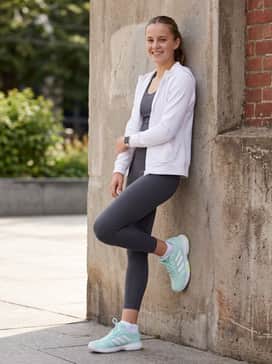 A sleek gym ensemble comprising high-waisted charcoal leggings and a matching sports bra, layered with an oversized white zip-up hoodie.