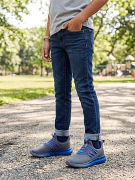 Dark wash slim-fit denim jeans worn with a heather grey pullover hoodie featuring a blue graphic logo and a matching blue baseball cap.