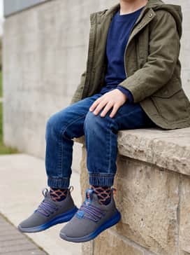 Olive green cargo joggers combined with a long-sleeve navy and white striped tee and a lightweight orange windbreaker for outdoor play.