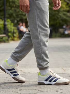 Lovb X Adidas Spezialist Indoor Shoes – Light grey tapered joggers paired with an oversized charcoal hoodie and a lime green beanie to coordinate with the shoe's vibrant accents.