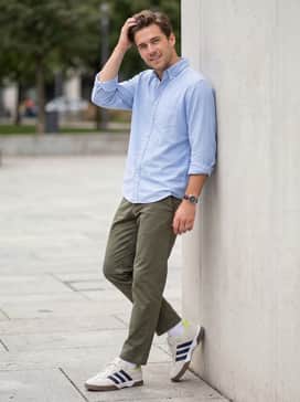 Lovb X Adidas Spezialist Indoor Shoes – Olive green chino trousers with a tucked-in light blue oxford shirt for a polished yet relaxed smart-casual ensemble.