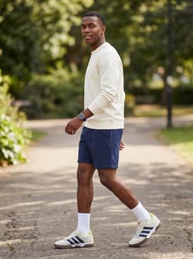 Lovb X Adidas Spezialist Indoor Shoes – Navy athletic shorts at mid-thigh length, a cream-colored graphic tee, and white crew socks for a classic retro-athletic summer look.