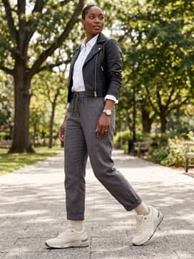 Tailored charcoal grey joggers worn with a crisp white button-down shirt and a cropped black leather jacket for an edgy urban aesthetic.