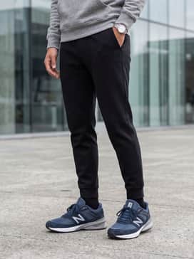 Tapered black tech-fleece joggers combined with a heathered grey hoodie and a lightweight puffer vest for a premium athletic aesthetic.