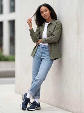 Relaxed-fit light wash vintage denim with a tucked-in graphic t-shirt and an open olive green utility shirt jacket.