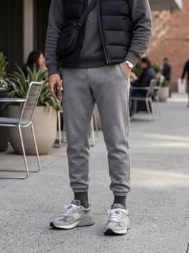 Grey tech-fleece joggers paired with a matching charcoal hoodie and a sleek black puffer vest for a high-end athletic leisure look.