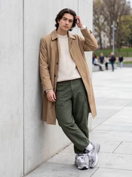 Wide-leg olive cargo pants, a cream-colored knit sweater, and a tan trench coat to lean into a sophisticated streetwear vibe.