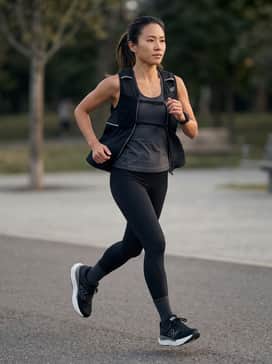 High-performance black compression leggings paired with a sleek, moisture-wicking charcoal racerback tank and a lightweight running vest.