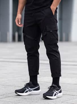Magic Speed 5 Wide – A sleek techwear-inspired outfit with black tapered cargo pants with strap details, an oversized white graphic hoodie, and a minimalist black utility vest for a modern urban vibe.