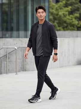 Black tapered joggers paired with a moisture-wicking tech tee in charcoal grey and a lightweight matte-finish bomber jacket for a sleek urban-athletic look.