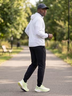 A sleek white windbreaker jacket paired with black utility joggers and a technical running cap for an urban athletic aesthetic.