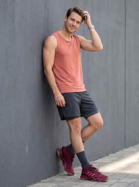 Mahomes 2 Impact Flx Tailgate Turf Training Shoes – A summer-ready athletic ensemble pairing charcoal 7-inch tech shorts with a coral-colored performance tank top that highlights the signature three-stripe accents.