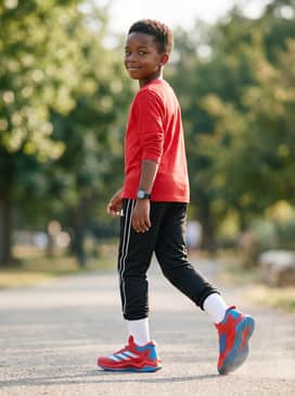 Marvel Spiderman Adizero Impact Turf Kids Shoes – Black track pants with white side stripes and a simple white long-sleeve tee for a clean, sporty streetwear aesthetic.