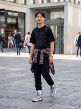 Max Aura 7 – An edgy streetwear outfit featuring charcoal grey cargo pants with multiple pockets, an oversized black graphic t-shirt, and a red flannel shirt tied at the waist to match the shoe's accents.
