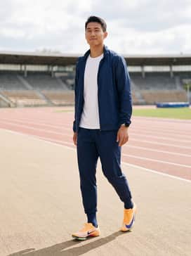 A sleek navy blue compression speed suit with orange side-panel accents to mirror the shoe's color palette.