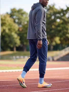 Athletic compression calf sleeves in black or navy paired with team-issue warm-up joggers and a technical windbreaker for pre-heat preparation.