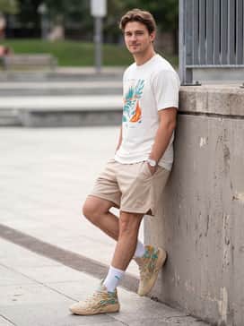 Mb04 Flare – Relaxed-fit beige mesh shorts worn with tall white crew socks and a white graphic tee featuring teal and orange typography.