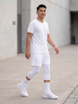 A full athletic look featuring white moisture-wicking basketball shorts, a matching gold-trimmed jersey, and white crew socks to highlight the shoe's wing silhouette.