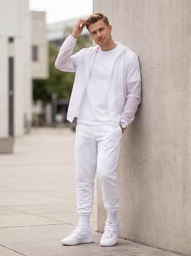 A clean monochrome outfit consisting of white joggers with a cinched ankle, a basic white heavyweight tee, and a translucent white windbreaker jacket.