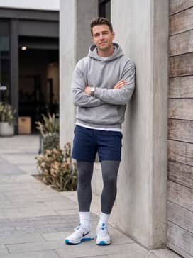 Modern streetwear styling with navy blue tech-fleece shorts, a heather grey oversized hoodie, and white ribbed crew socks to draw attention to the blue outsole.