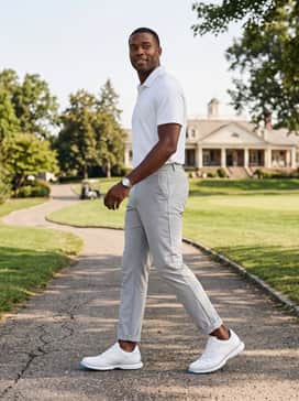 White technical golf trousers and a mint green performance polo, accented with a grey woven belt to emphasize the shoe's clean lines.