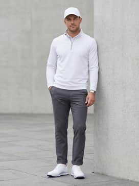 A modern athletic ensemble pairing charcoal grey tech-fleece joggers with a fitted white quarter-zip pullover and a matching white sports cap.