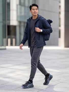 Tapered black tech-fleece joggers, a dark grey moisture-wicking t-shirt, and a lightweight navy windbreaker for a cohesive, athletic-inspired look.