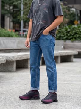 Straight-leg medium wash blue jeans rolled at the hem, a vintage-inspired 90s graphic t-shirt in dark tones, and a silver chain necklace for a nostalgic Y2K-inspired streetwear look.