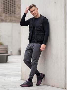 Megaride S2 Shoes – Tech-focused tapered joggers in charcoal grey, a moisture-wicking compression long-sleeve top, and a black utility vest with multiple pockets for a modern, functional aesthetic.