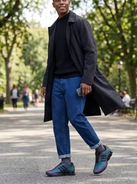 A modern streetwear set including dark indigo tapered jeans, a black mock-neck knit sweater, and a long technical trench coat to let the iridescent colors pop.