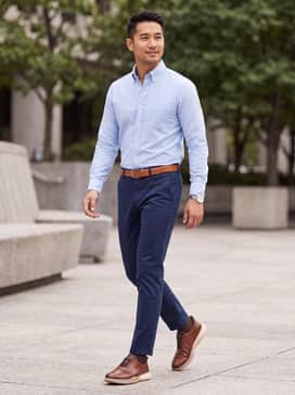 Navy blue slim-fit chinos paired with a light blue oxford button-down and a coordinating tan leather belt.