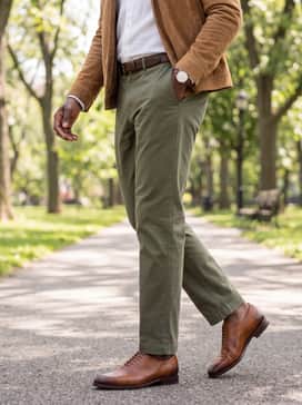 Olive green chinos paired with a white linen button-up shirt and a tan suede bomber jacket, finished with a matching brown leather belt for a relaxed yet polished weekend outfit.