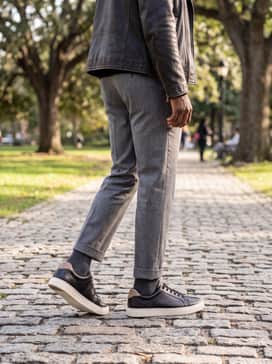 Go for a sophisticated transition look with grey wool trousers, a black merino wool turtleneck, and a leather biker jacket, letting the cream sole provide a subtle pop of contrast.