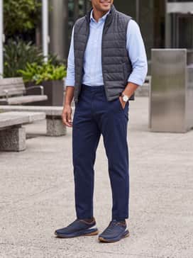 Mens Grandpr Allday Golf Shoes – Slim-fit navy blue chinos worn with a light blue button-down oxford shirt and a quilted vest for a polished casual office outfit.