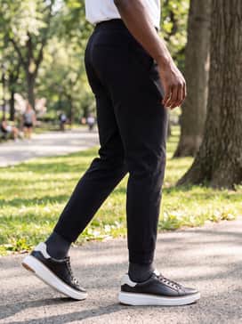 Black tailored joggers, a grey heathered hoodie, and a structured black overcoat for a sleek, elevated athleisure aesthetic.