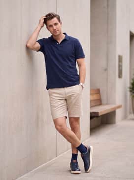 Style with beige tailored shorts and a navy blue pique polo for a sophisticated yet breathable summer weekend ensemble.
