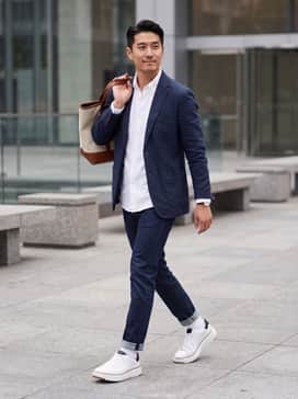 Mens Grandpr Topspin Sneakers – Slim-fit dark indigo denim jeans paired with a crisp white button-down shirt and a navy unstructured blazer for a polished casual Friday look.