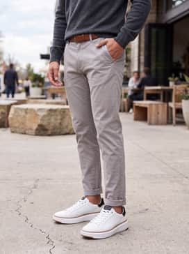 Light grey tailored chinos worn with a charcoal grey cashmere crewneck sweater and a brown leather belt to mirror the gum sole accents.