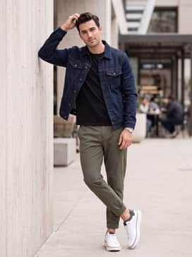 Olive green tech-fabric joggers paired with a high-quality black t-shirt and a structured denim jacket for a contemporary streetwear vibe.