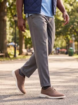 Medium grey dress pants with a light blue polo shirt and a quilted navy vest for a stylish transitional-weather outfit.