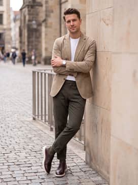 Tapered olive green trousers worn with a crisp white crewneck tee and an unstructured khaki blazer for a contemporary smart-casual vibe.