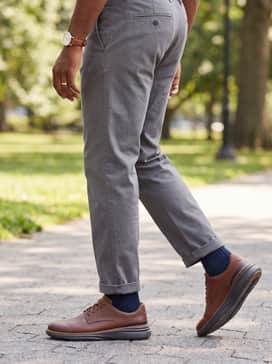 Medium grey dress slacks paired with a light blue oxford cloth button-down shirt and a navy V-neck sweater for a polished and approachable professional outfit.