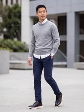 Navy blue slim-fit chinos paired with a crisp white button-down shirt and a light grey merino wool sweater for a polished office look.