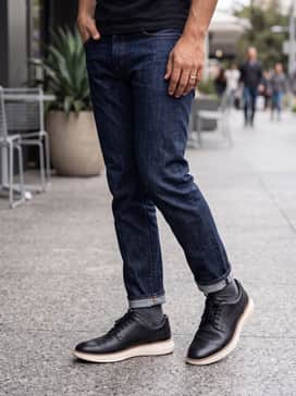Dark indigo raw denim jeans with a charcoal grey polo shirt and a tailored navy blazer for a sophisticated evening out.