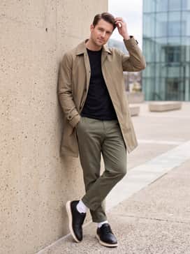 Olive green tapered trousers worn with a black pima cotton t-shirt and a khaki technical trench coat for an elevated streetwear aesthetic.