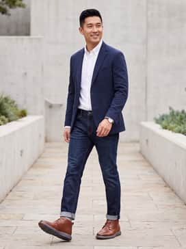 Slim-fit dark wash denim paired with a crisp white button-down shirt and a navy blue unstructured blazer for a refined business-casual look.