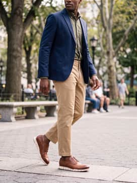 Olive green chinos combined with a light blue oxford cloth button-down shirt and a structured navy blazer for a classic preppy-meets-modern style.